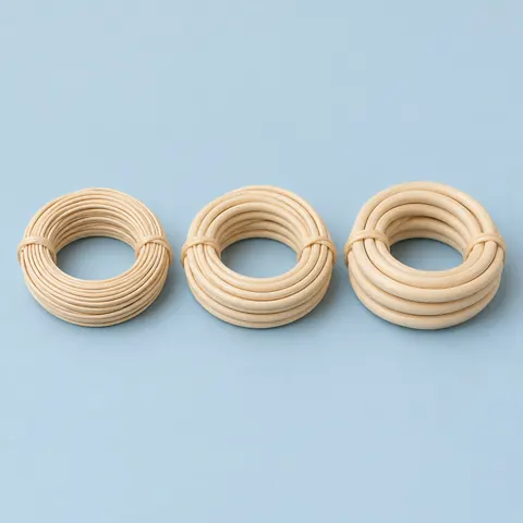 Three small coils of natural reed spline side by side in three thicknesses on a dusty blue backdrop