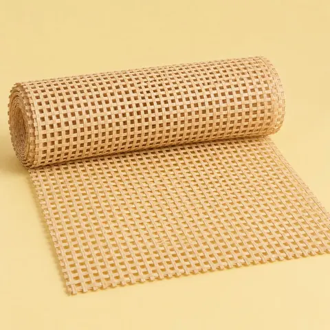 Roll of natural square weave cane webbing partly unrolled on a butter yellow paper backdrop