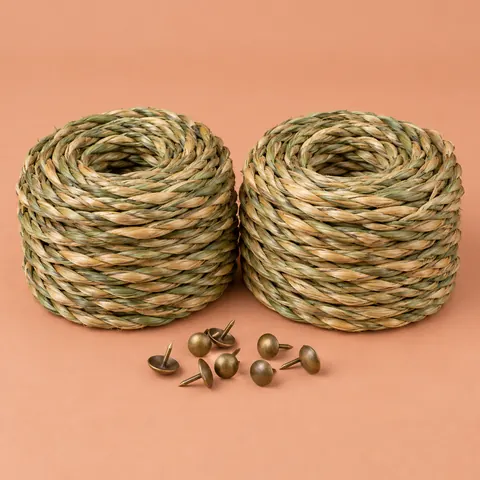 Two coils of green-to-wheat twisted seagrass cord side by side with a few upholstery tacks on terracotta paper