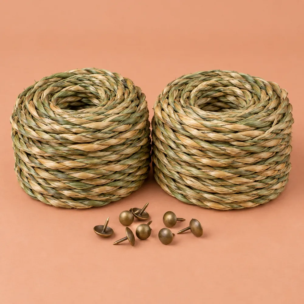 Two coils of green-to-wheat twisted seagrass cord side by side with a few upholstery tacks on terracotta paper