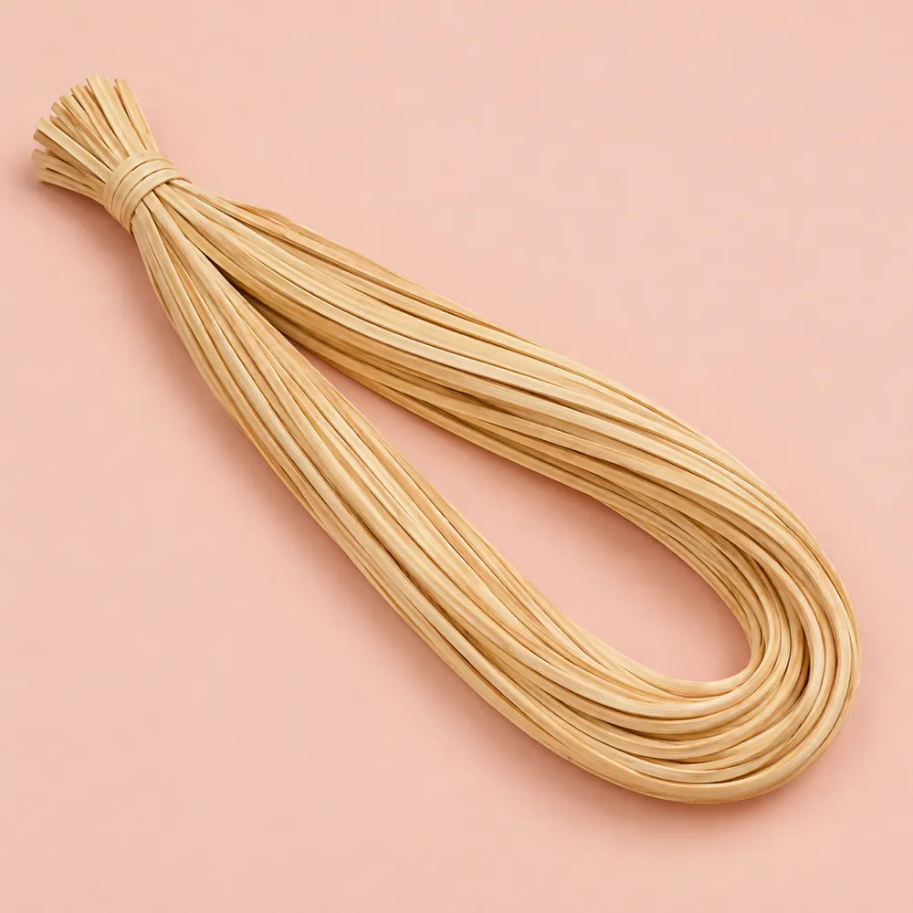Looped hank of glossy honey-blond strand chair cane, tied at one end, on a soft pink paper backdrop