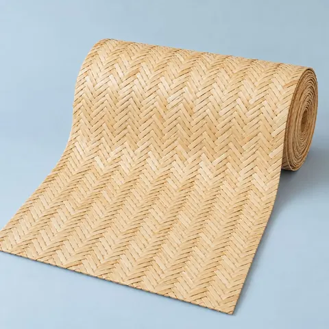 Roll of natural herringbone cane webbing partly unrolled on a pale blue paper backdrop