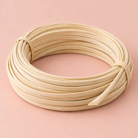 Coil of matte, pale cream flat oval reed, flat on one side and rounded on the other, on a soft pink backdrop