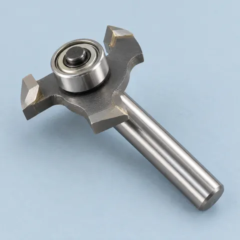 Carbide slot cutter router bit with a ball bearing on top and a plain 1/4 in steel shank, lying on a dusty blue backdrop