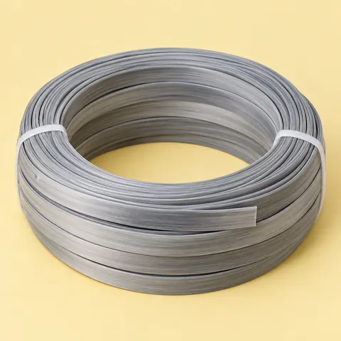 Tied coil of two-tone gradient grey flat PE wicker strip on butter yellow paper