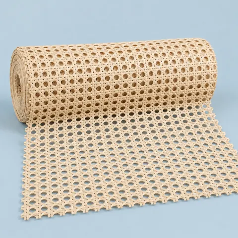 Roll of semi-bleached open weave cane webbing in a pale cream tone, partly unrolled on a dusty blue backdrop