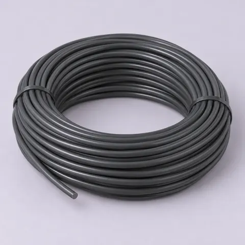 Tied coil of smooth dark grey round PE wicker strand on pale lavender paper